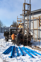 Drilling for water with truck and metall drill, blue pipes for inside installing