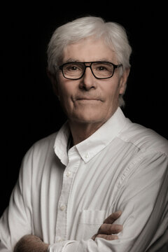 Studio portrait of older gentleman with grey hair.
