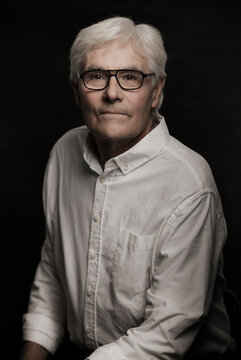 Studio portrait of older gentleman with grey hair.