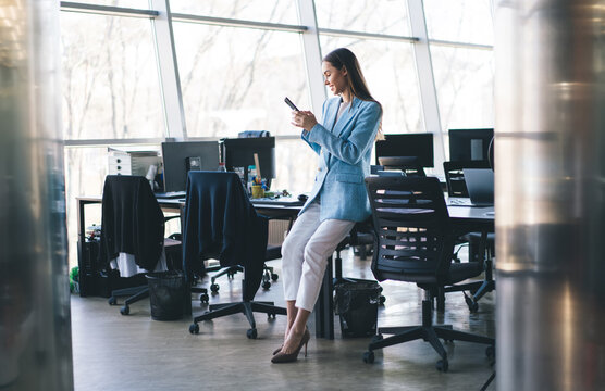 Woman using smartphone while sitting on table in office