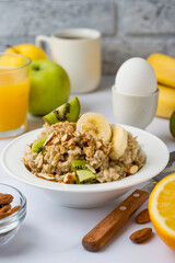 Oatmeal with fruits and nuts, orange juice, egg in a stand, traditional, healthy breakfast. Proper nutrition, diet..