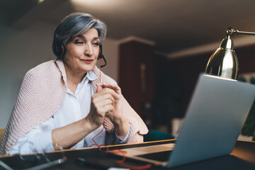 Happy mature woman using laptop in living room