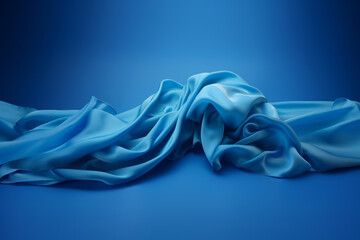 A blue piece of cloth on a blue background, presenting dynamic still lifes, flowing fabrics, and sculpted textures. - obrazy, fototapety, plakaty