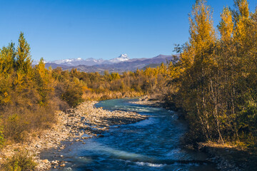 Beautiful autumn landscape mountain river, yellowed trees, mountains with snowy peaks. Charming mountain landscape in autumn - Powered by Adobe