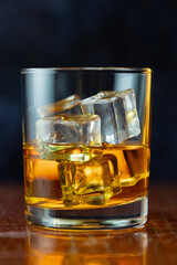 A glass of whiskey and ice old polished table on dark background