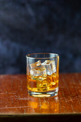A glass of whiskey and ice old polished table on dark background