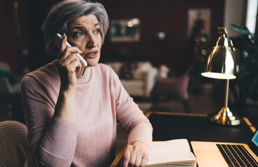 Thoughtful mature woman talking on smartphone