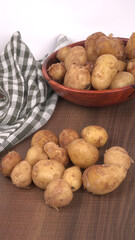 Fresh small potatoes for cooking in a wooden bowl. With copy space on white background.