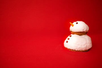 A little cute snowman made of cookies and white cream with chocolate buttons and eyes. Bright red...