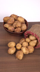 Fresh small potatoes for cooking in a wooden bowl. With copy space on white background.