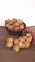 Fototapeta premium Fresh small potatoes for cooking in a wooden bowl. With copy space on white background.