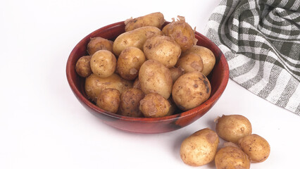 Fresh small potatoes for cooking in a wooden bowl. With copy space on white background.