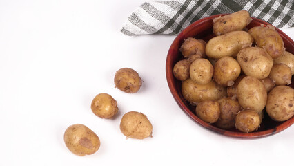 Fresh small potatoes for cooking in a wooden bowl. With copy space on white background.