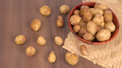 Fresh small potatoes for cooking in a wooden bowl. With copy space on white background.