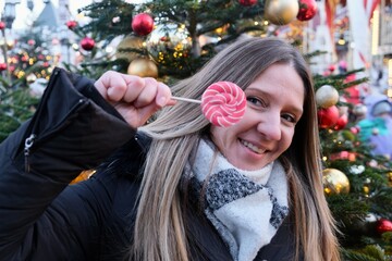 Portrait of a young woman at a Christmas fair with a bright candy. The concept of Christmas and New...
