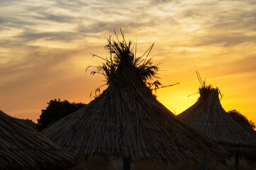 Sunset over thatched beach umbrellas