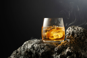 Whiskey with ice and smoke on a grey stone.