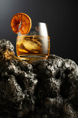 Old fashioned cocktail with ice and dried orange slice.