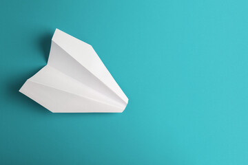Flat lay of white paper plane on pastel blue color background