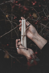 Three white candles tied with twine in a woman's hand