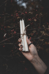 Three white candles tied with twine in a woman's hand