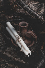 Three white candles tied with twine next to a wooden candlestick