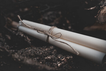 Three white candles tied with twine on a background of nature