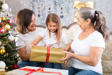 Portrait of grandmother, mother and girl at Christmas on sofa bonding, loving and enjoying holiday season