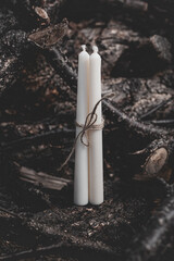Three white candles tied with twine on a background of nature