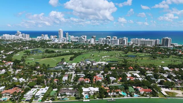 Drone view of La Gorce Club, private tropical paradise located near Miami Beach with luxury oceanfront buildings, lots of mansions and golf course under blue southern sky