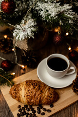 Espresso coffee, croissant near christmas tree on table. Coffee break