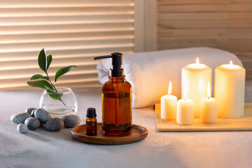 Beauty spa treatment items on white wooden table. Candles, stones, essential oils and towels. Cosy...