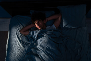 Arabic young man lying in bed cannot sleep from insomnia. unable sleep. Restless people.