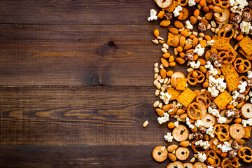 Fast food and salty snacks background. Pretzels nuts and chips top view