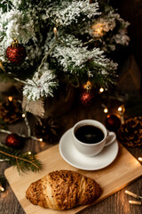 Espresso coffee, croissant near christmas tree on table. Coffee break