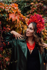 Ukrainian woman in red autumn wreath in park in nature. Autumn