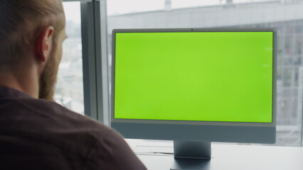 Man watching mockup computer workplace. Freelancer reading greenscreen monitor