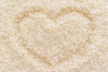 Uncooked rice with heart shape background. Parboiled rice texture backdrop. Cooking preparation in the kitchen concept.