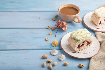Roll biscuit cake with cream cheese and jam, cup of coffee on blue wooden, side view, copy space.