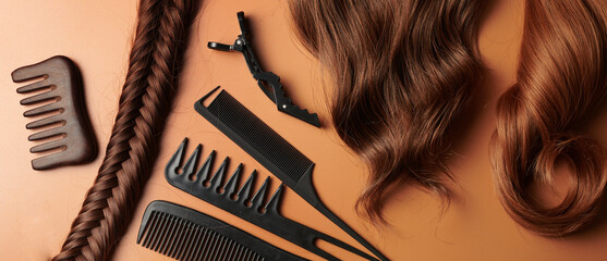 Hairdresser tools close-up isolated on orange background. Curls of brown hair and a set of combs,...