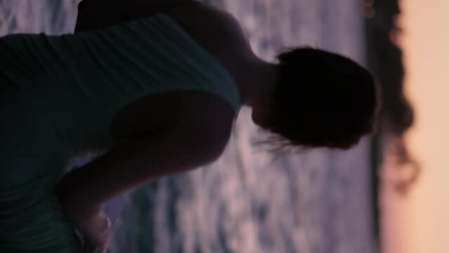 Silhouette of a young woman against the background of the sea, squeaking a letter and throwing sheets of paper into the wind