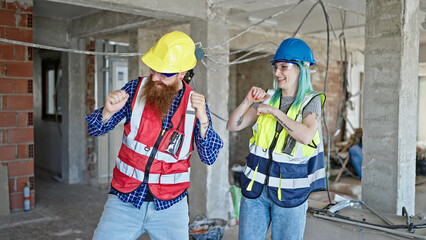 Man and woman builders smiling confident dancing at construction site