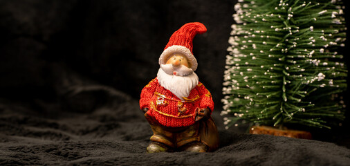 Weihnachtsmann neben verschneitem Tannenbaum, schwarzer Hintergrund, Panorama