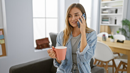 Vibrant, confident blonde boss woman sparking success with smartphone talk & enjoying espresso in elegant office interior