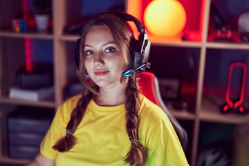 Young blonde woman streamer sitting on table with relaxed expression at gaming room