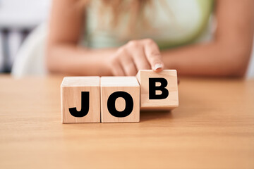 Fototapeta premium Young woman holding cubes with job word on the table