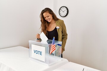 Young beautiful hispanic woman electoral table president putting vote in box at electoral college