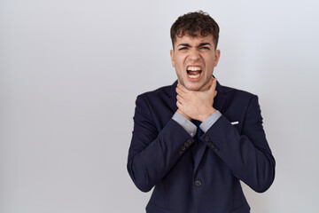 Young hispanic business man wearing suit and tie shouting and suffocate because painful strangle....