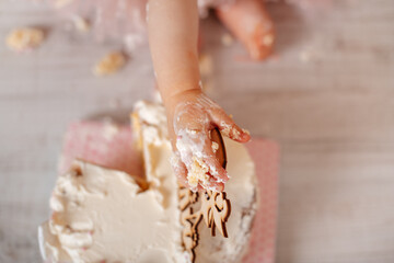 A close-up of a tiny hand covered in frosting, reaching for a delicious cake.