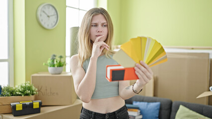 Young blonde woman holding color test thinking at new home